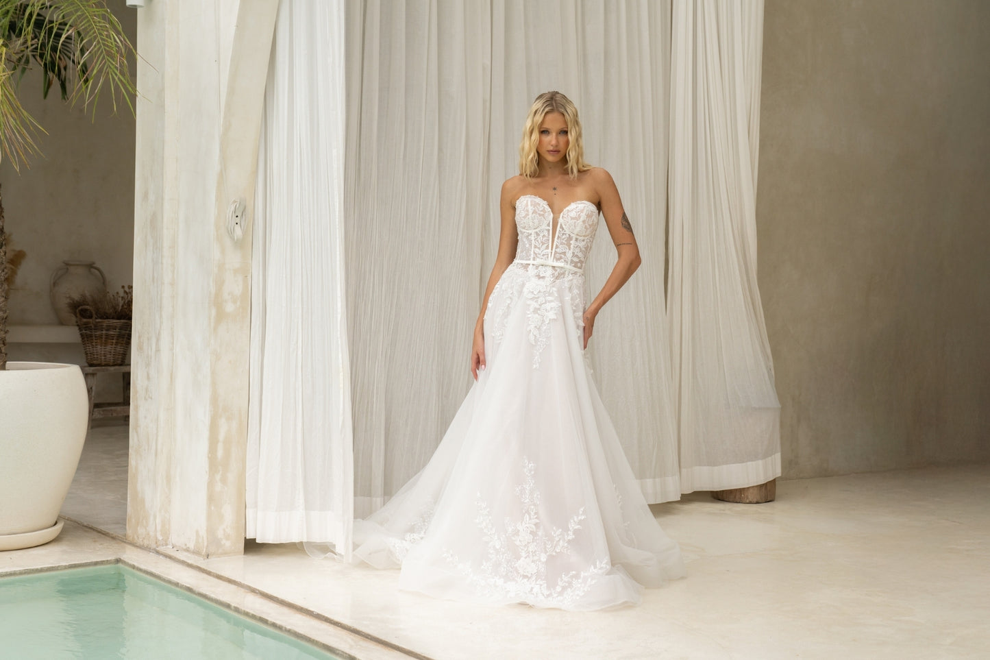 A-line wedding dress with v-plunge sweetheart neckline, floral lace, waistbelt and subtle basque waist, flowing tulle skirt.
