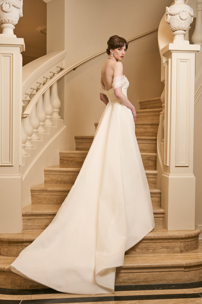 Back view of model wearing tamsin overskirt. A detachable overskirt with structured lining.