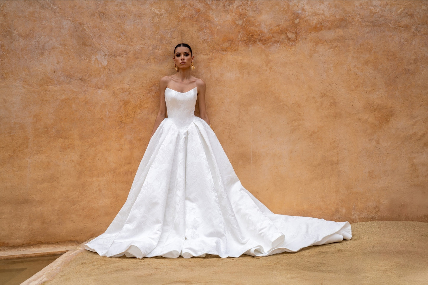 dramatic A-line wedding dress in floral jacquard fabric, featuring a steep basque waist and cat-eye neckline