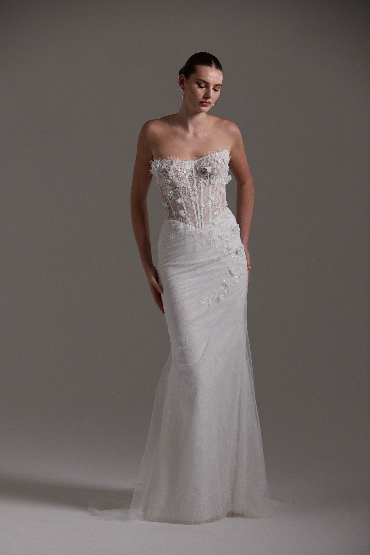 Fitted Bridal gown with floral lace scattered around the corseted bodice, basque waistline.
