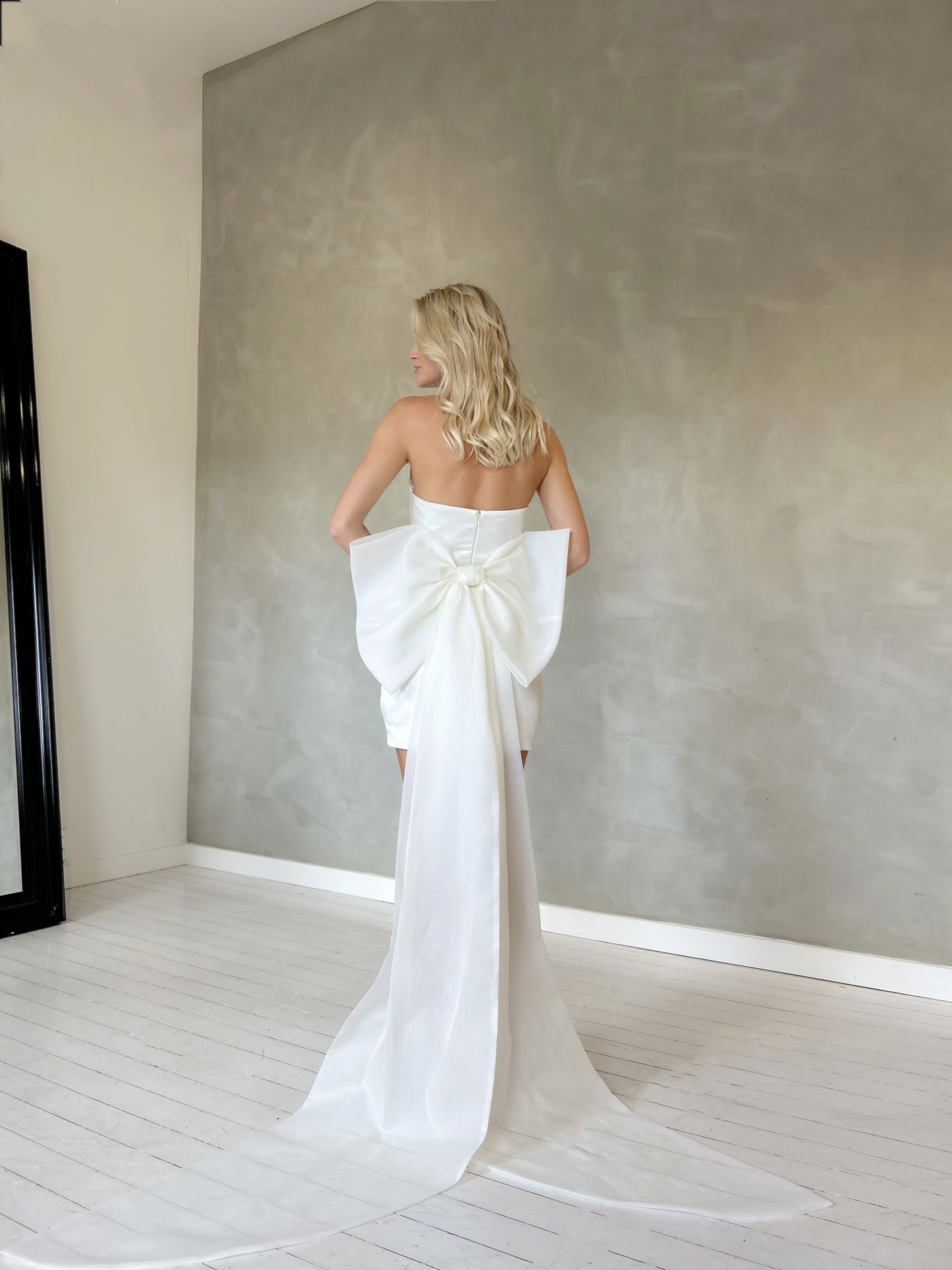 Fitted mini wedding dress in satin fabric, featuring a strapless sweetheart neckline with ruching