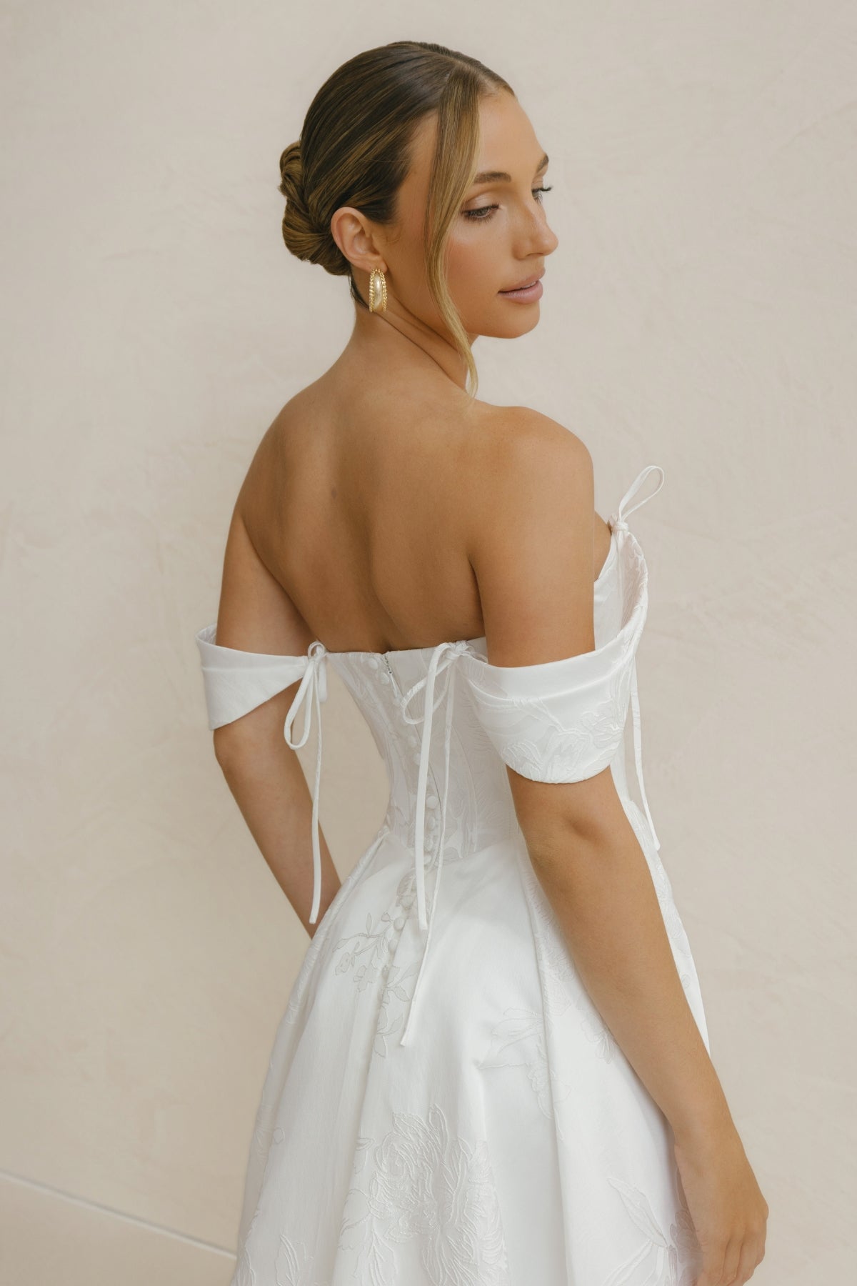 A-line wedding gown in Floral Jacquard fabric, off-the-shoulder sleeves, pleated skirt. 