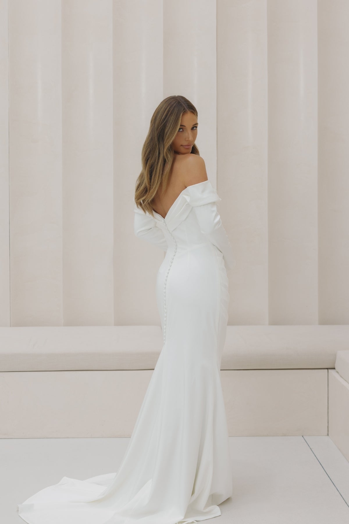 Satin fitted gown with off the shoulder neckline and long sleeves. 