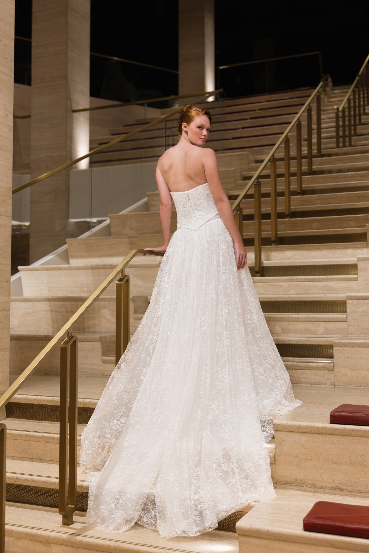 BLAKE strapless lace corset A-line wedding dress with ruffled trim and basque waist, full-length back view on a staircase, by Atelier Wu