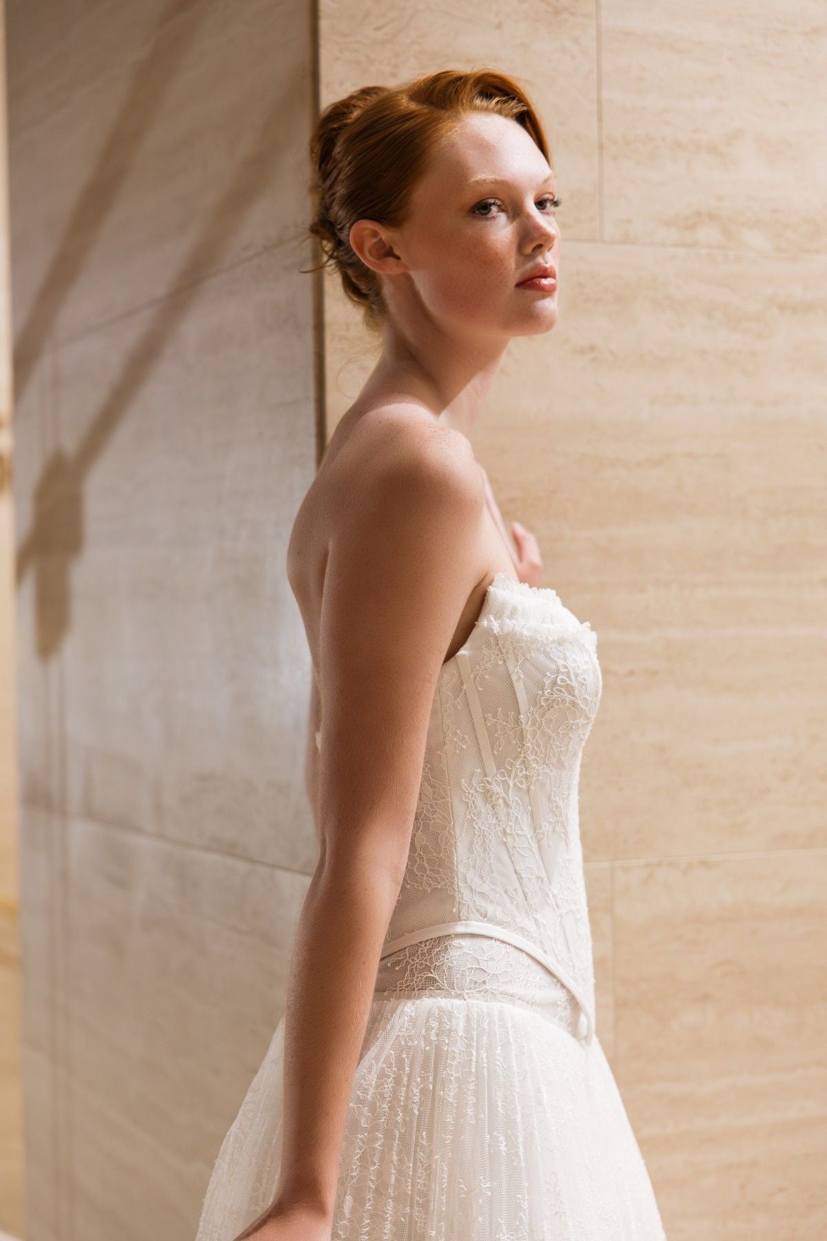 BLAKE strapless lace corset A-line wedding dress with ruffled trim and basque waist, side profile close-up, by Atelier Wu