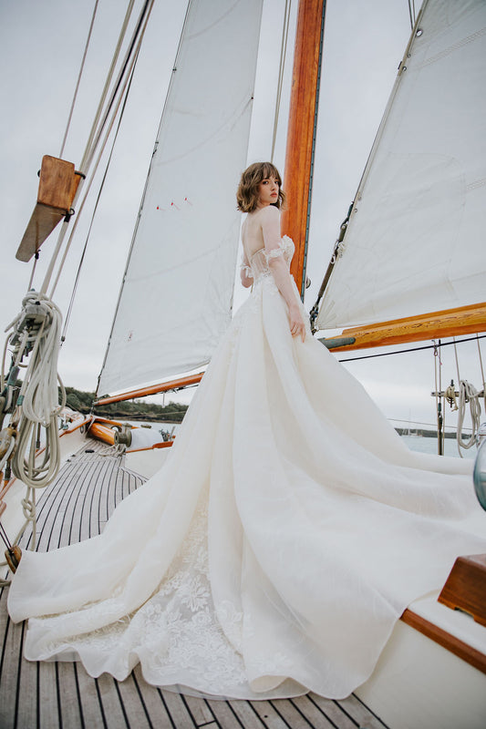 Back view of model wearing Orla overskirt. Ivory organza is paired with lace to create this voluminous detachable overskirt