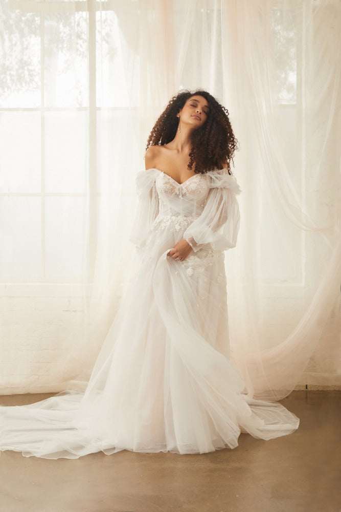 Model wears sky gown with detachable balloon sleeves made from silky tulle
