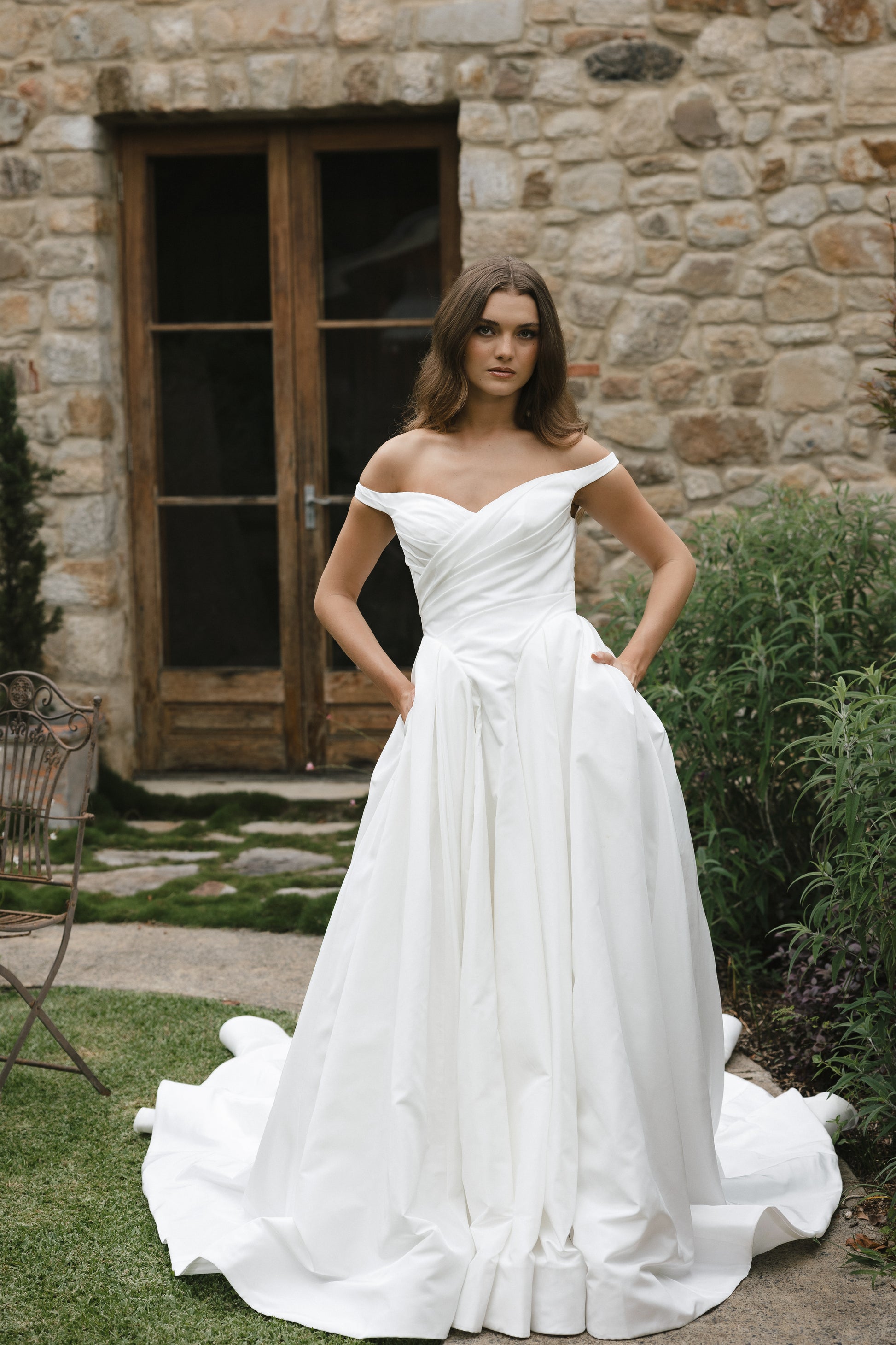 Bridal gown Jodie features a clean A-line silhouette, off-shoulder sweetheart neckline, and basque waistline. Made from Taffeta, it’s designed for a timeless walk down the aisle by Roselle Collection Jessica Couture.