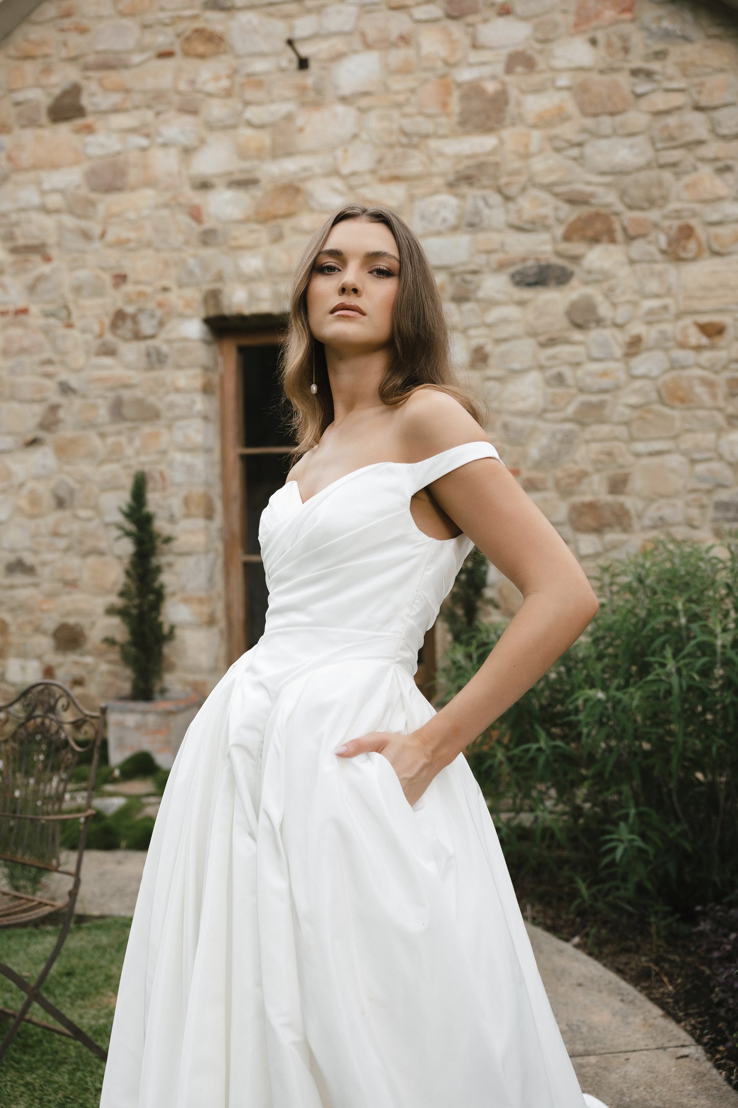 Bridal gown Jodie features a clean A-line silhouette, off-shoulder sweetheart neckline, and basque waistline. Made from Taffeta, it’s designed for a timeless walk down the aisle by Roselle Collection Jessica Couture.