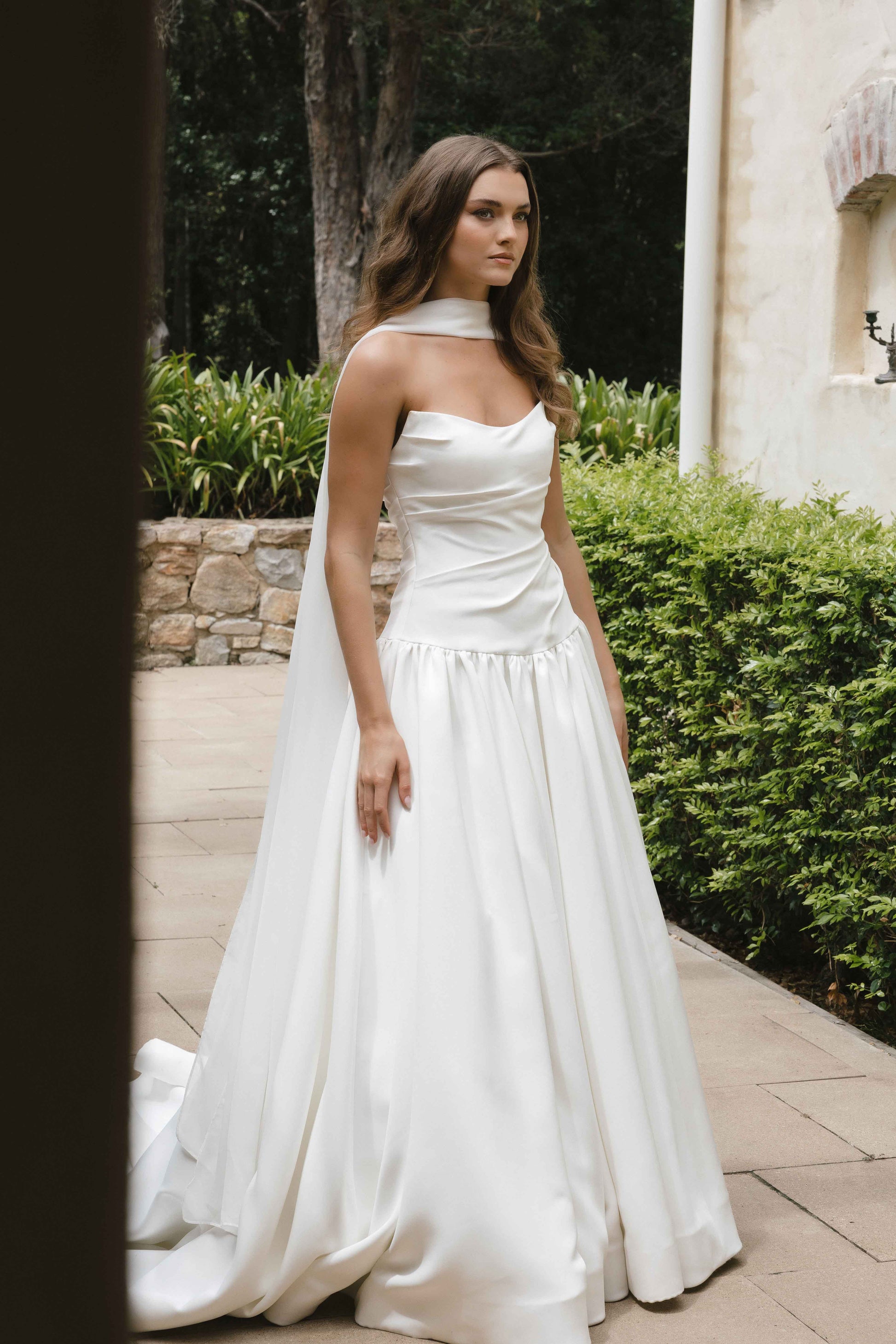 Jana Gown – A-line drop-down waist silhouette with a cat-eye bodice and draped ruching, paired with the Tonica scarf. By Roselle Collection, Jessica Couture.