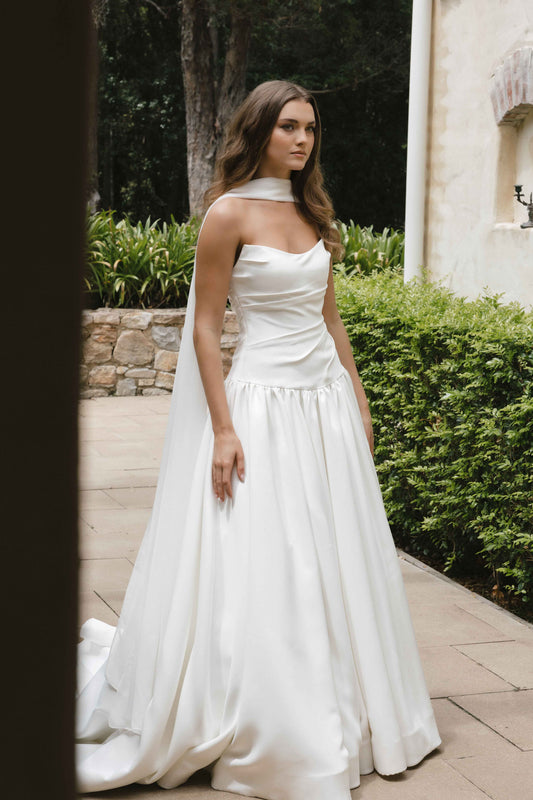 Jana Gown – A-line drop-down waist silhouette with a cat-eye bodice and draped ruching, paired with the Tonica scarf. By Roselle Collection, Jessica Couture.