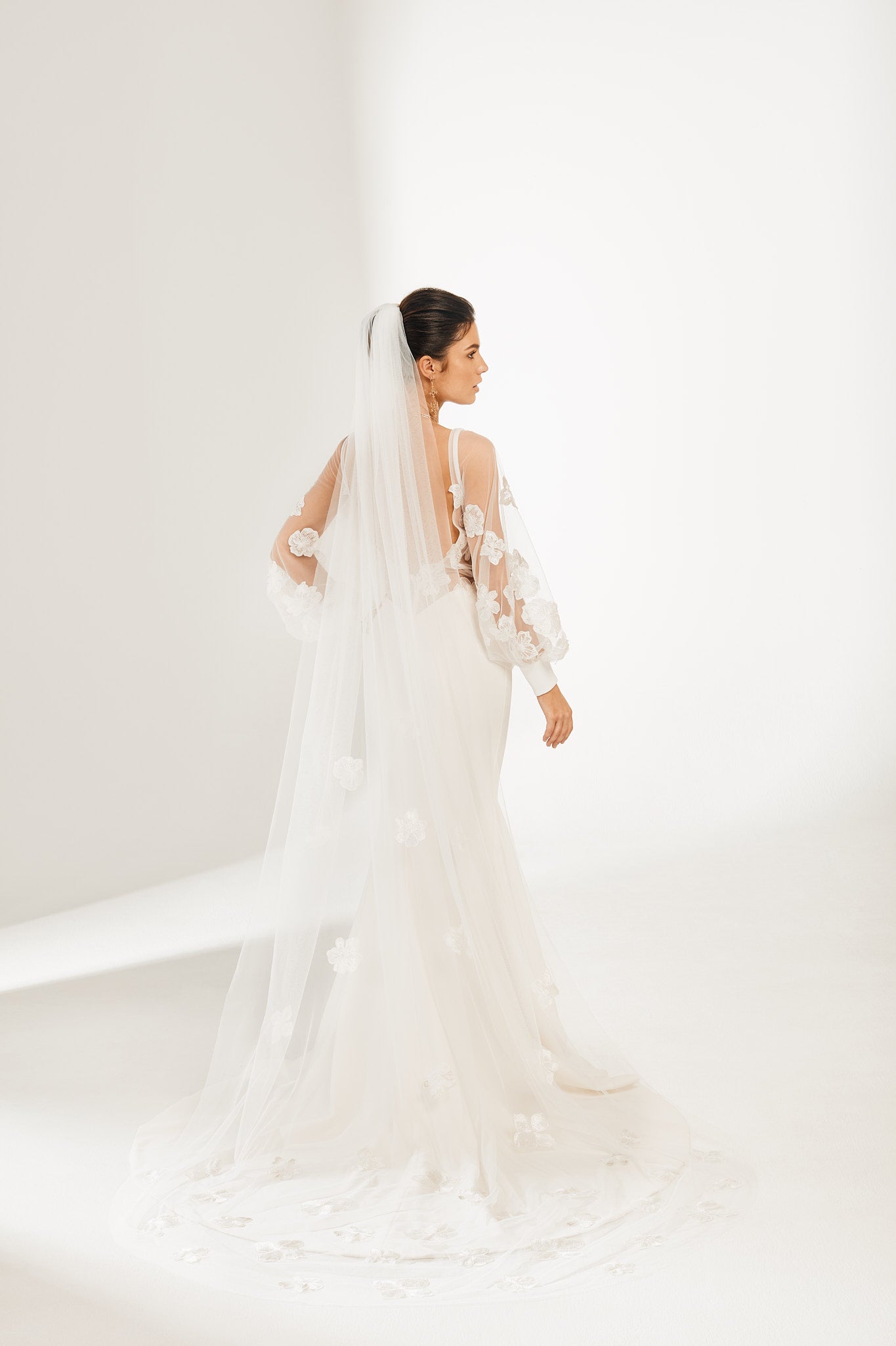 Bride wears white in all white room with Orangina Veil with embroidered flowers