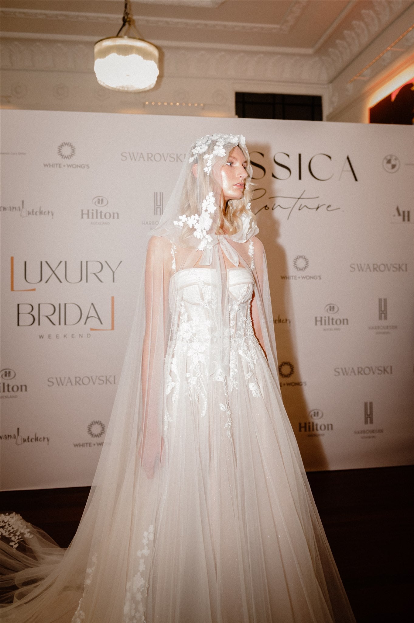 Model wears cape with hood made from silky tulle and 3D florals