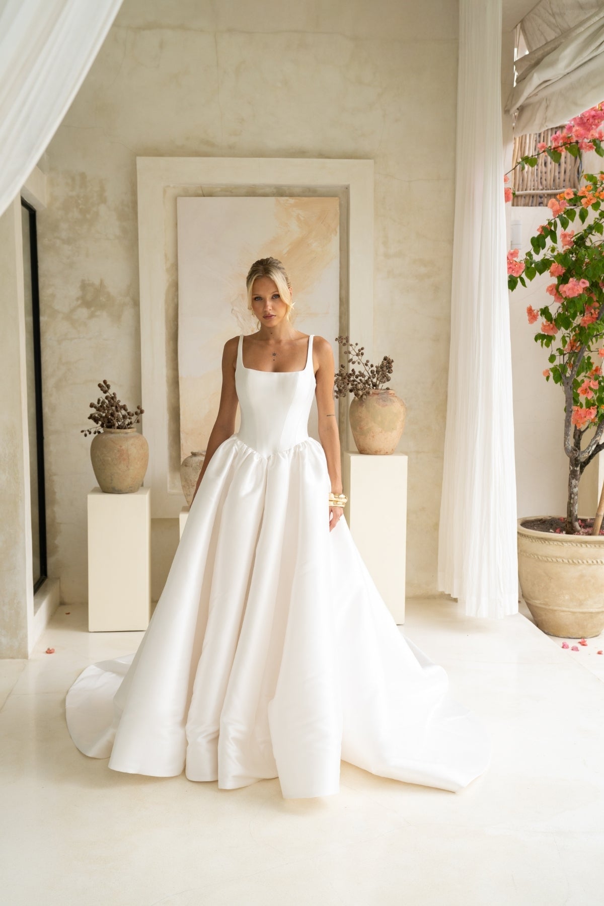 Dramatic A-line wedding gown featuring a squared neckline with straps. subtle basque waist with ruching all around waistline. chapel train. 