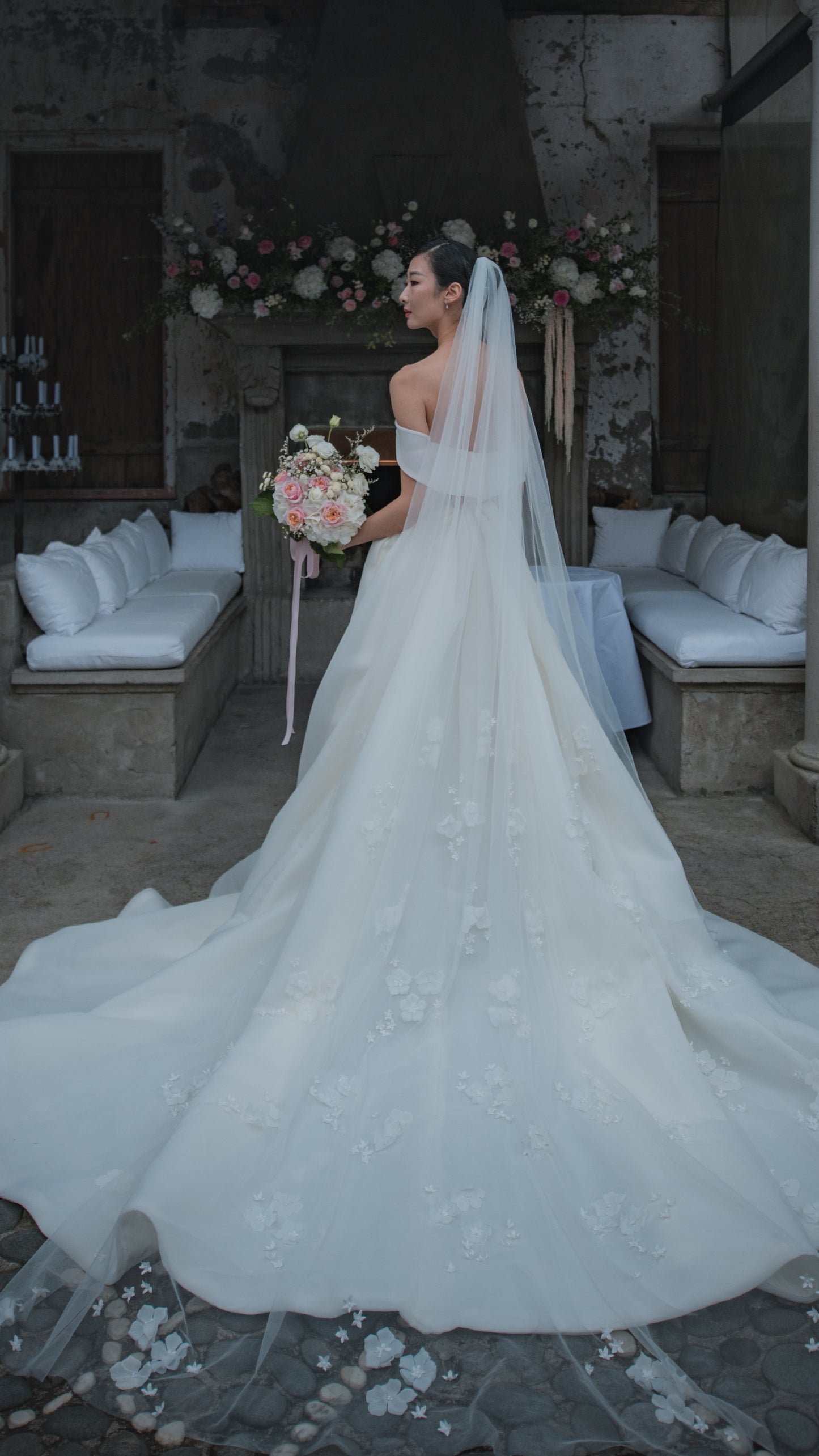 Back view of bride wearing dress with large train and 3D floral veil