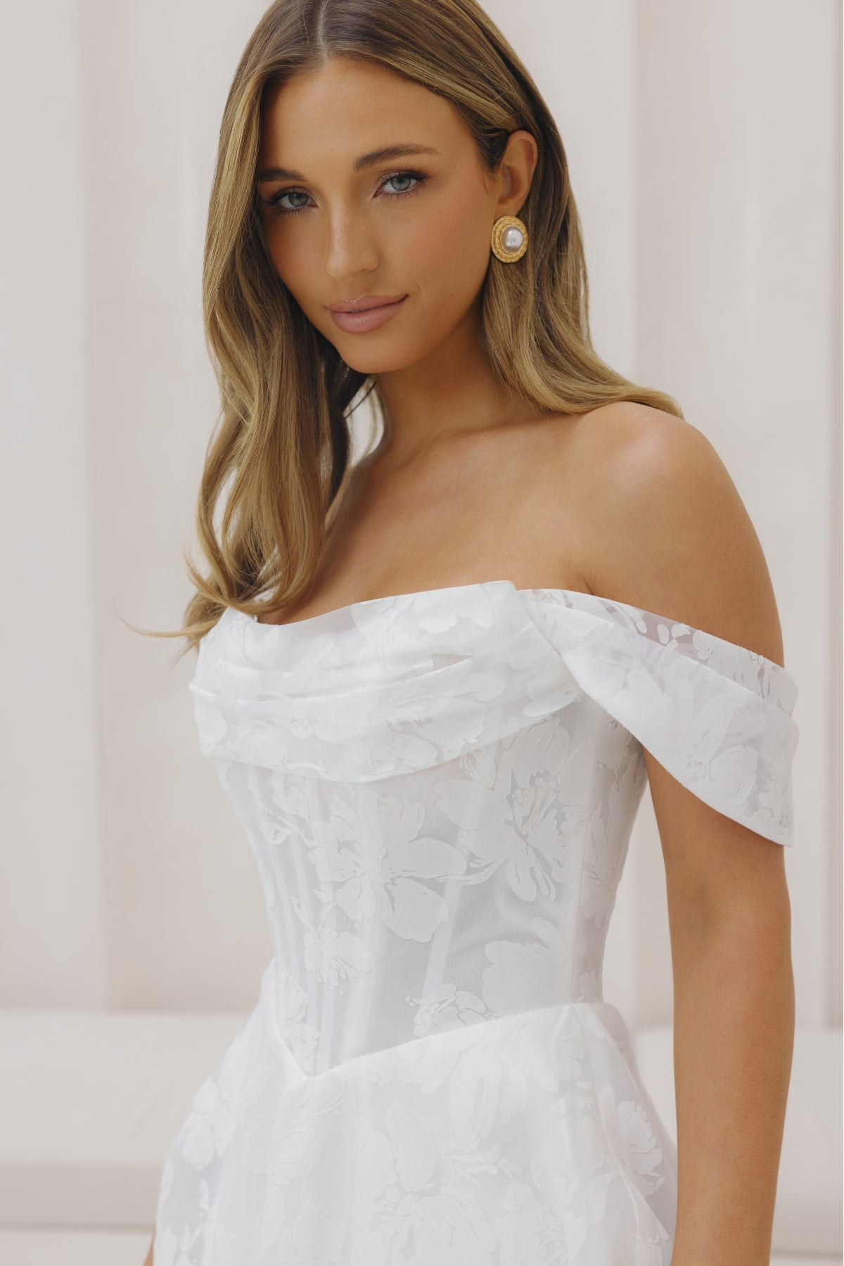 A-line wedding gown with off the shoulder neckline, ruched bust, and jacquard organza fabric. 