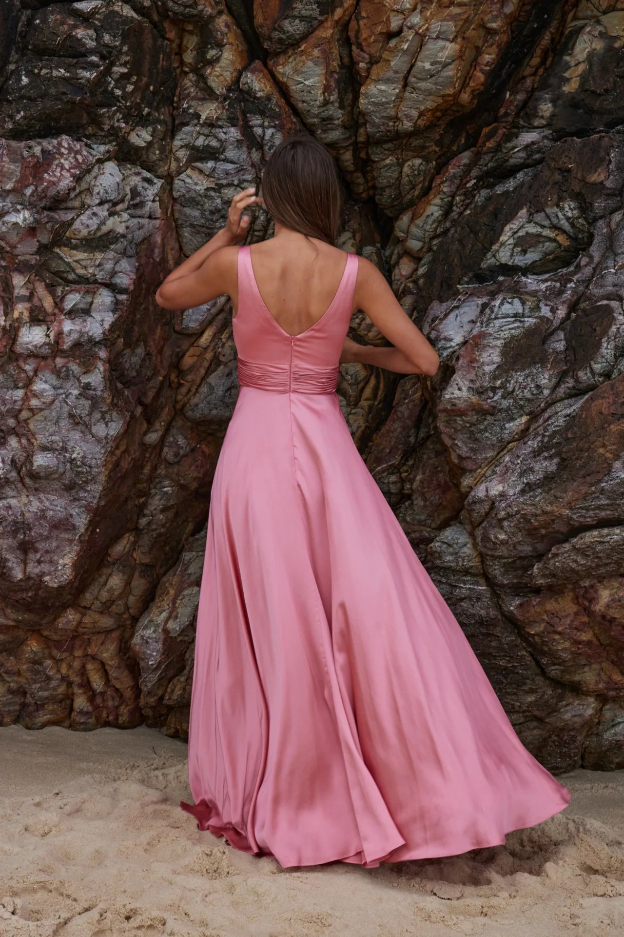 Back view of sakura gown with V-backline and ruched waistband with full-length skirt in pink satin fabric