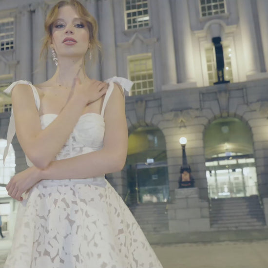 A-line mini Bridal dress with laser cut floral lace detailing featuring a
square neckline with ribbon straps 