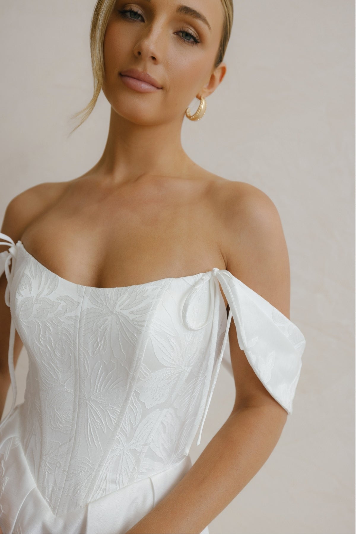 A-line wedding gown in Floral Jacquard fabric, off-the-shoulder sleeves, pleated skirt. 