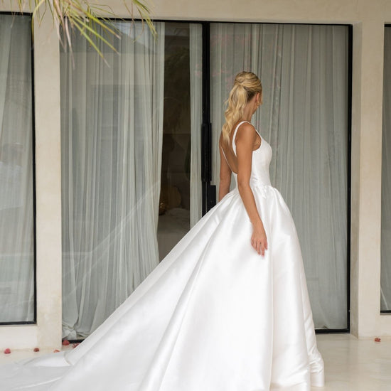 Dramatic A-line wedding gown featuring a squared neckline with straps. subtle basque waist with ruching all around waistline. chapel train. 
