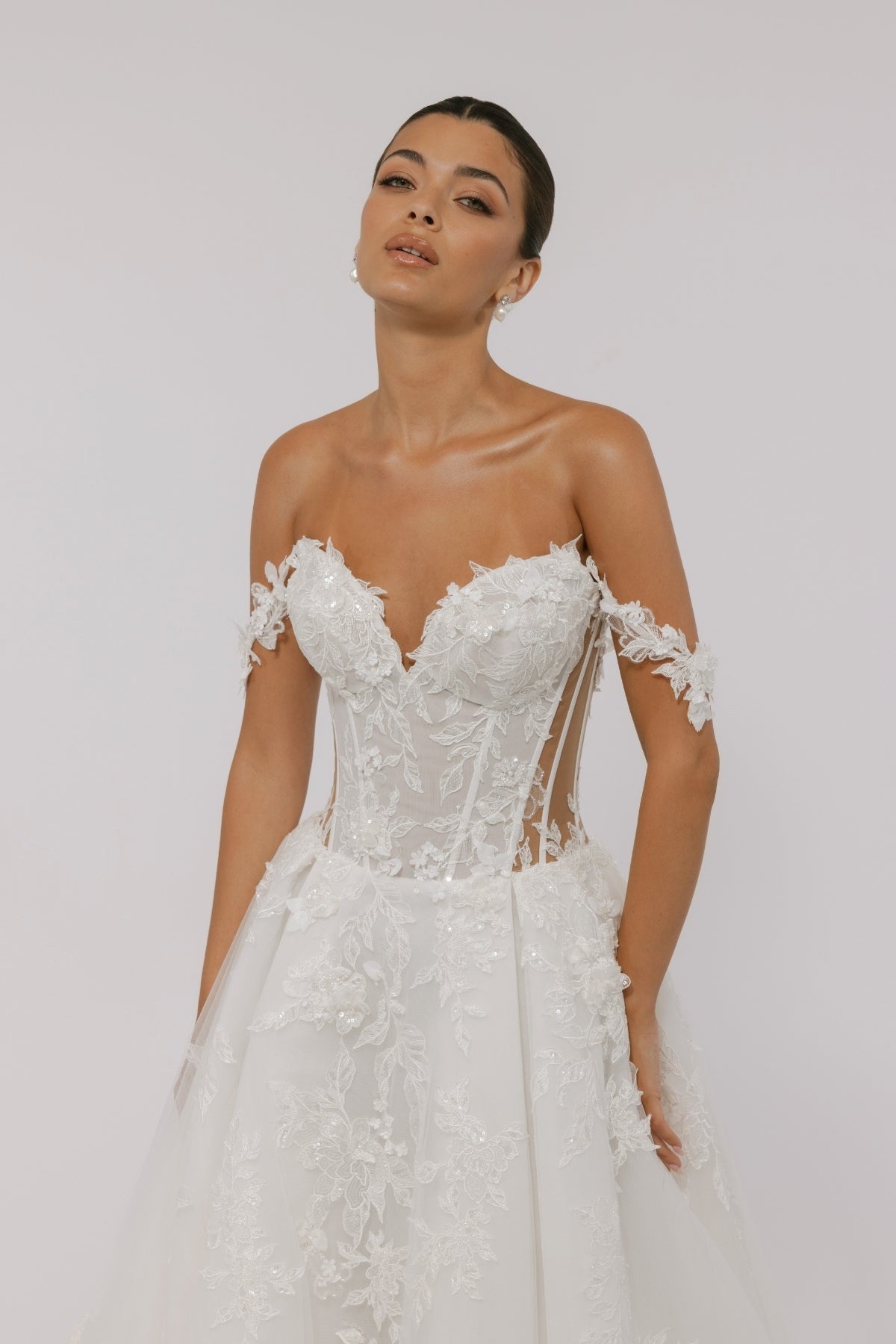 wedding dress featuring off the shoulder straps, sweetheart neckline, sheer boning on the sides, and floral lace A-line skirt 