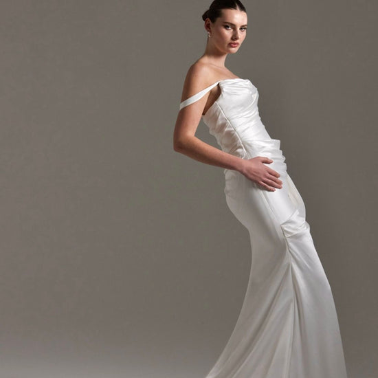 fitted satin wedding dress with pleats across bust and hips. Featuring off the shoulder straps. 