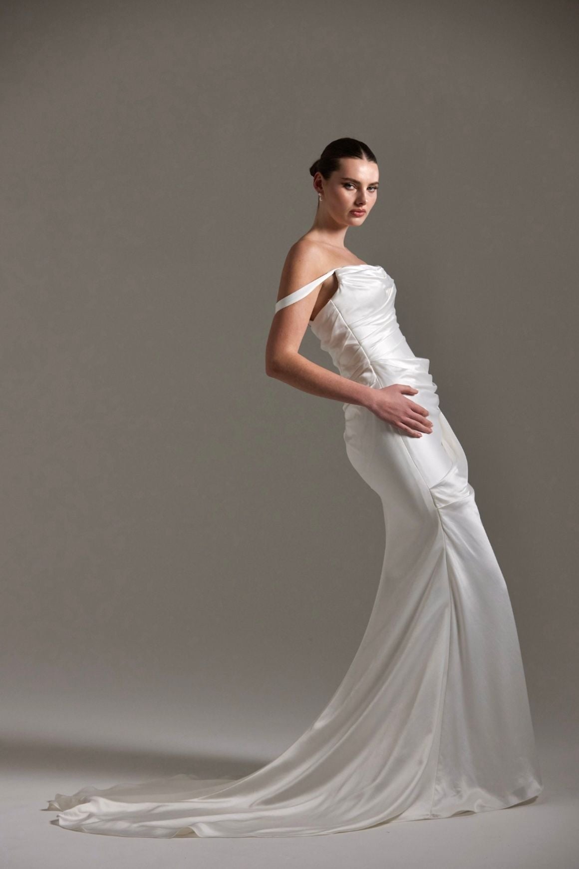 fitted satin wedding dress with pleats across bust and hips. Featuring off the shoulder straps. 