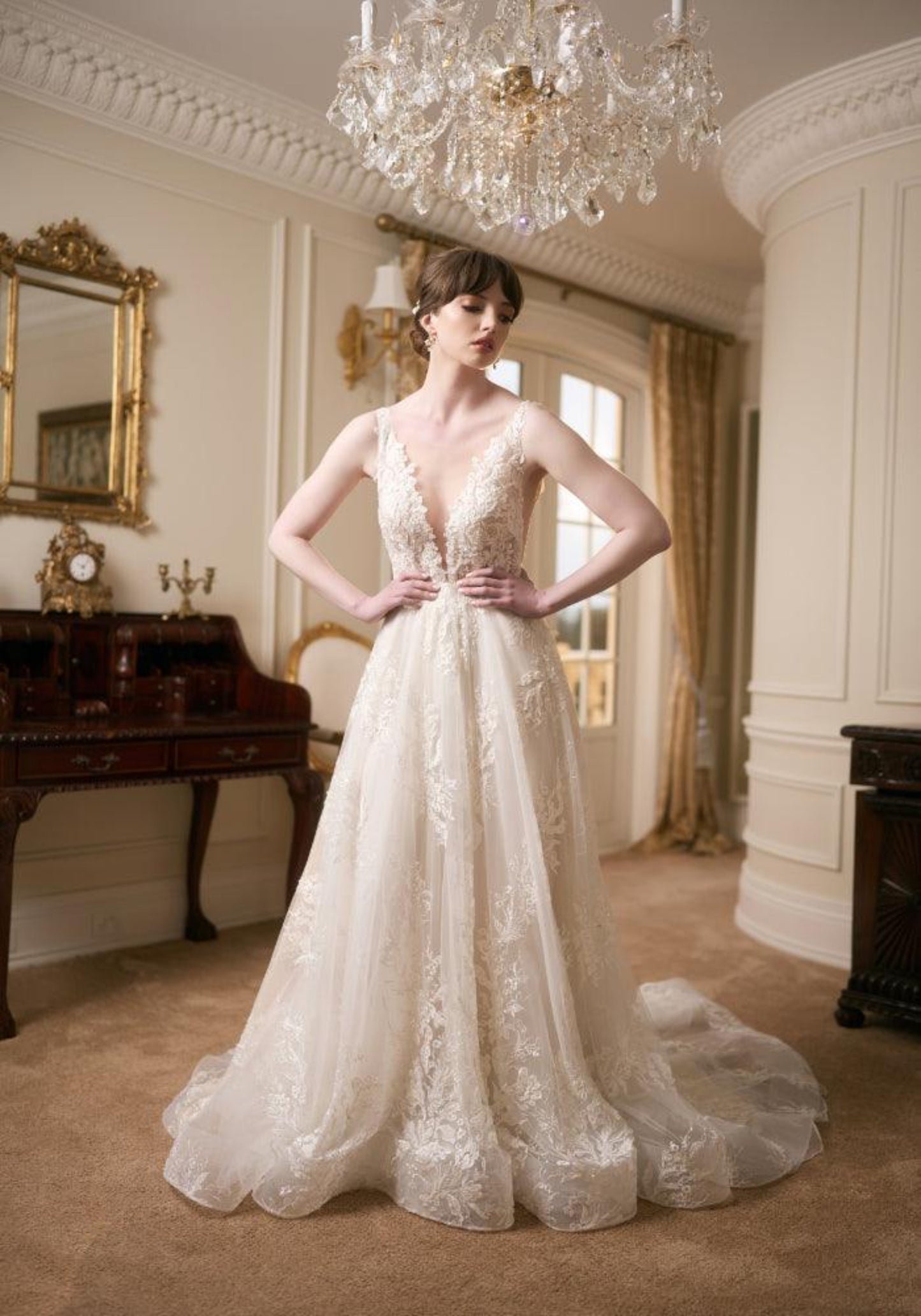 Ivory full-length wedding gown with plunging V-neckline, lace applique and a-line skirt. Embroidered with pearls and beads.
