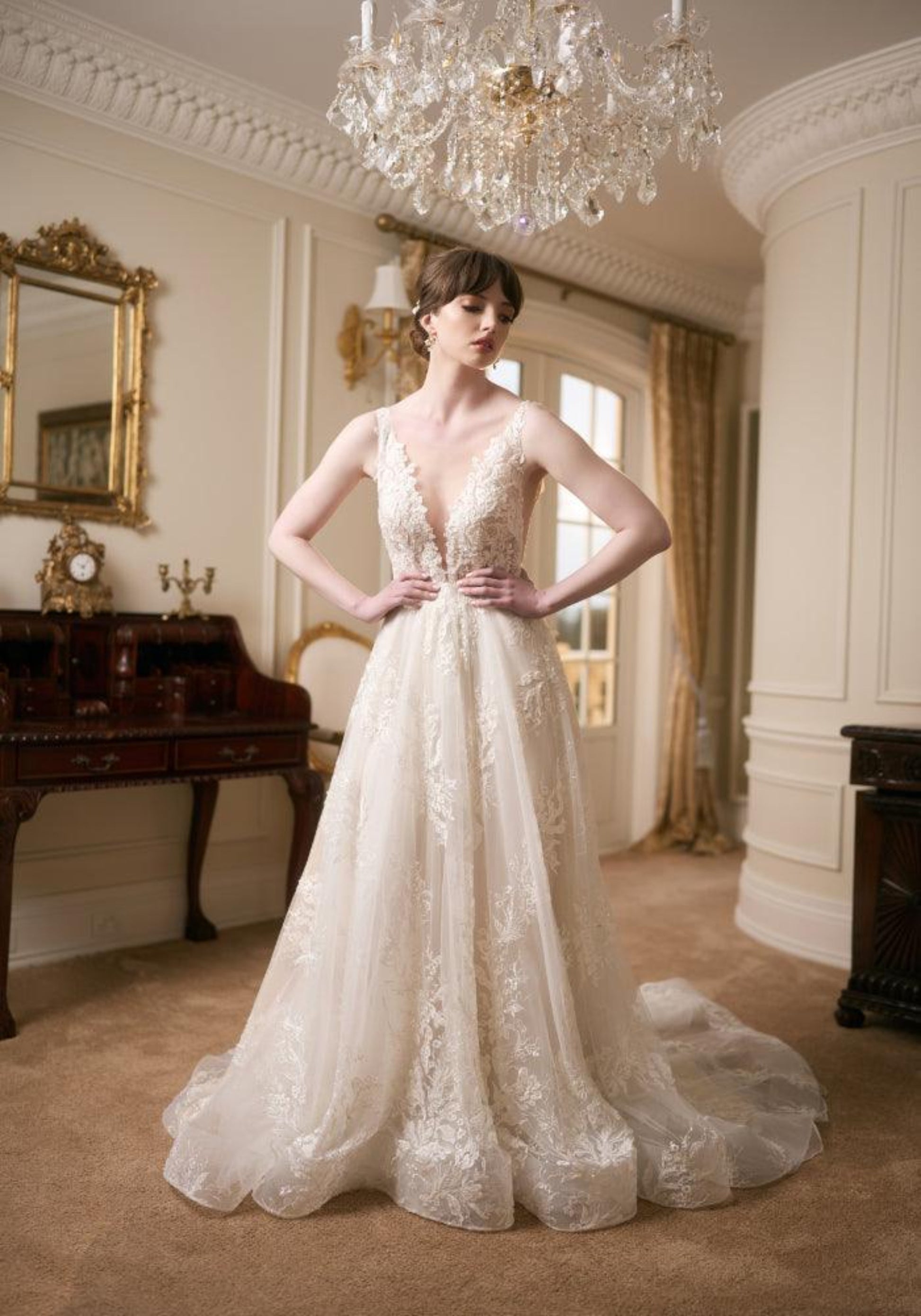 Ivory full-length wedding gown with plunging V-neckline, lace applique and a-line skirt. Embroidered with pearls and beads.