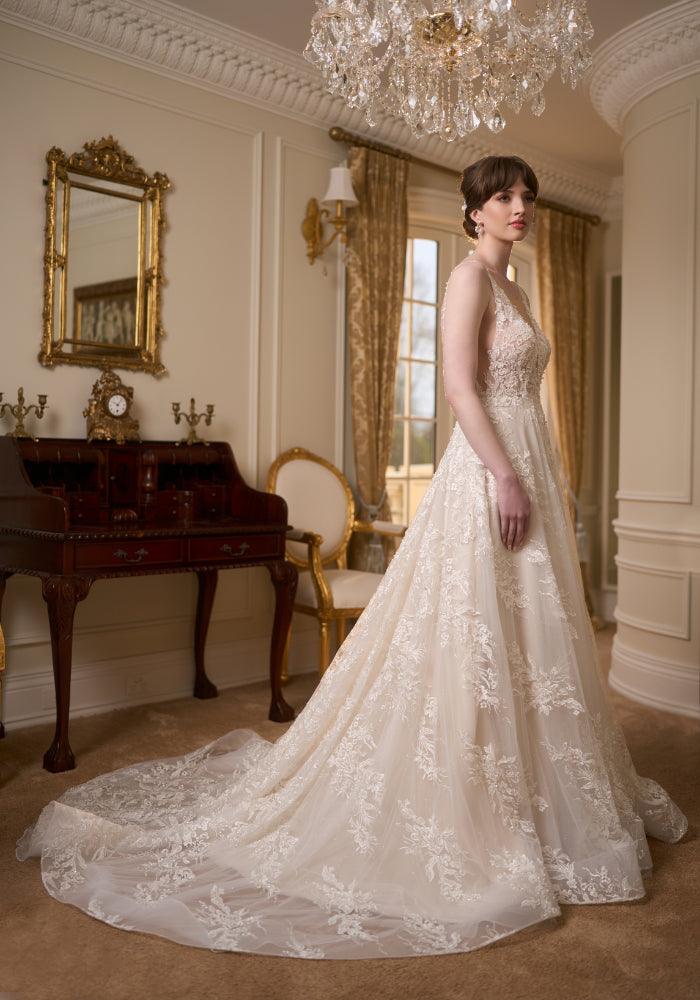 Side view of ivory full-length wedding gown with plunging V-neckline, lace applique and a-line skirt. Embroidered with pearls and beads. Illusion mesh at sides of bodice.