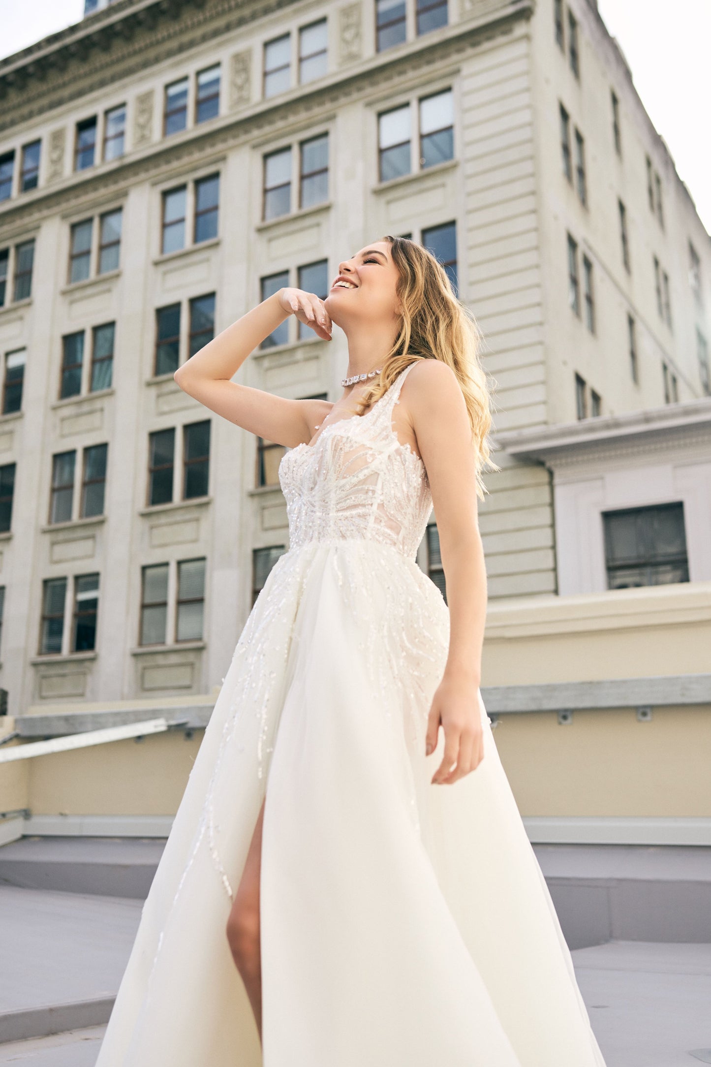 Raffael wedding dress from Jessica Coutures. Square neckline, low back A-line dress with organza fabric and glitter detailing at the bodice. Boning support, cinched waist, dramatic skirt. Hidden features include pockets and a split for easy movement.