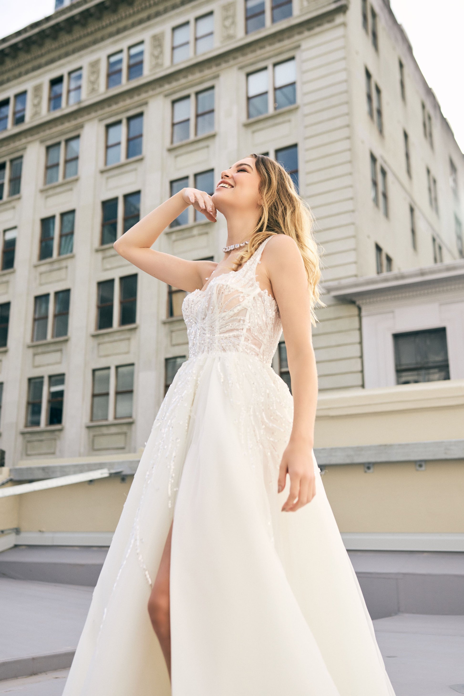 Raffael wedding dress from Jessica Coutures. Square neckline, low back A-line dress with organza fabric and glitter detailing at the bodice. Boning support, cinched waist, dramatic skirt. Hidden features include pockets and a split for easy movement.