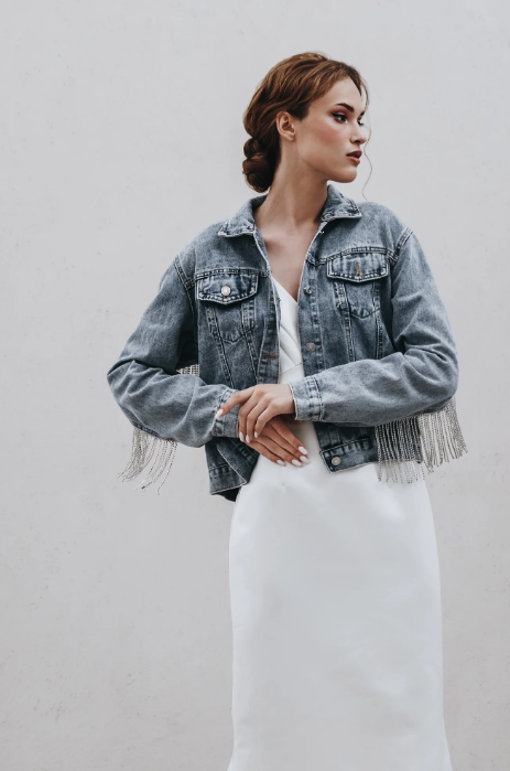 Front view of blue denim jacket with diamante fringe over white slip dress