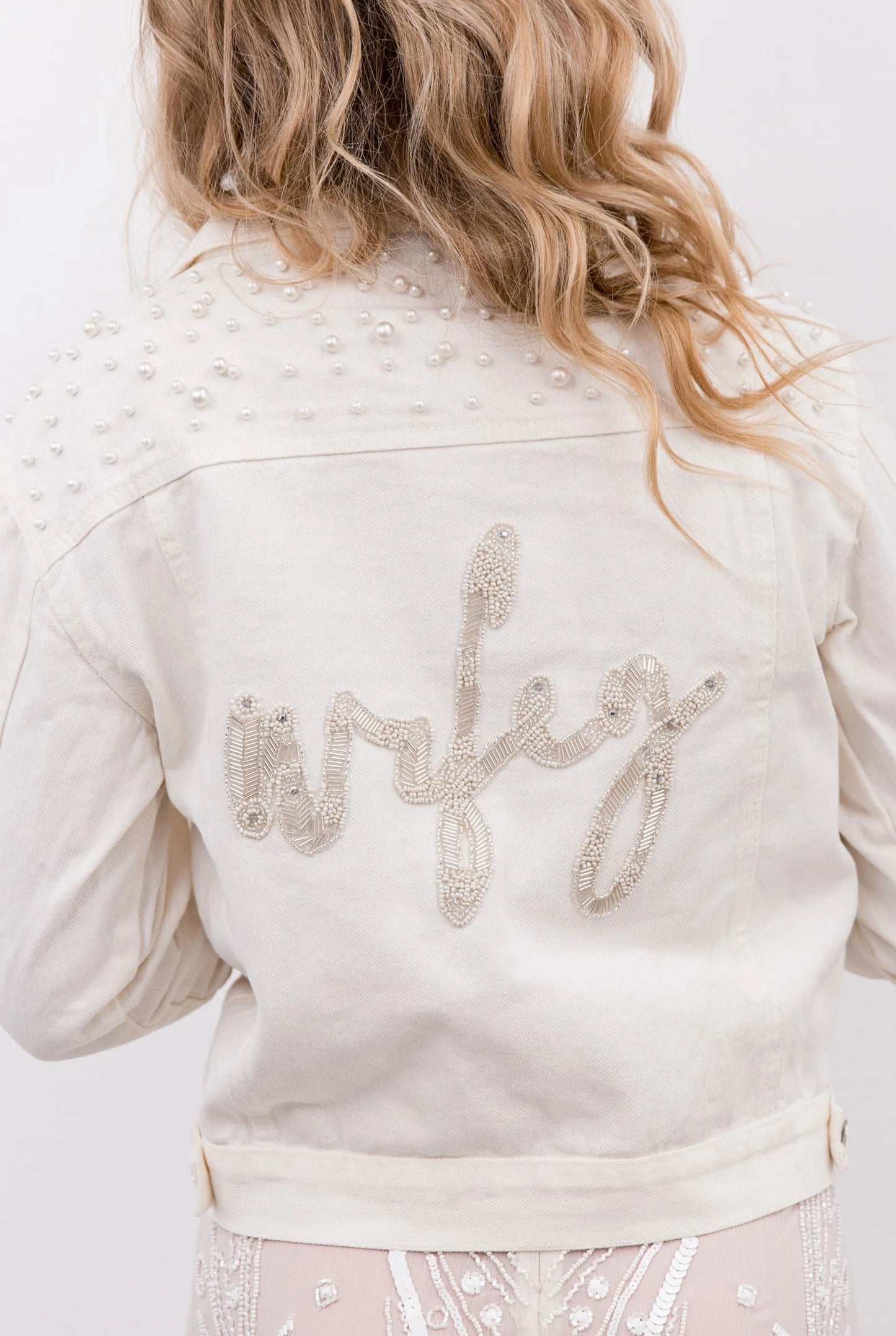 White denim jacket with pearl studs and 'wifey' beaded on the back